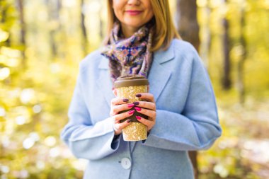 Sonbahar, içecekler ve insanlar kavramı - kadının elinde sıcak bir içecek fincan