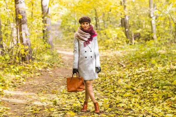Seizoen, de natuur en de mensen concept - vrouw in herfst park poseren met tas — Stockfoto