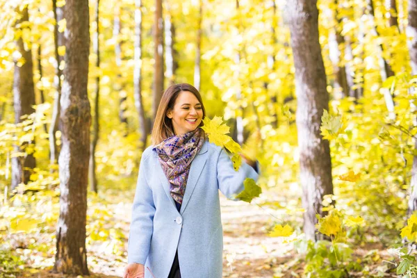 Herfst, natuur en leuk concept - mooie jongedame in blauwe vacht gooien boeket van bladeren — Stockfoto