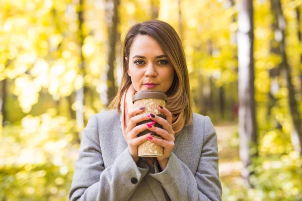 Conceito de outono, natureza e pessoas - Close up de mulher de casaco cinza segurando uma xícara de café — Fotografia de Stock