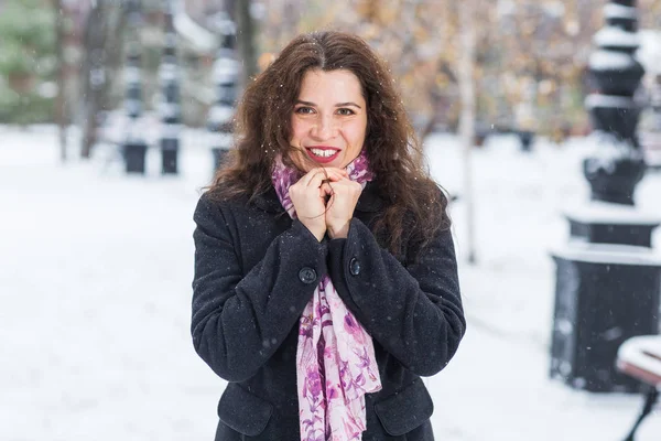 Stad, winter en mensen concept - mooie gelukkig jonge vrouw in zwarte jas en roze sjaal in besneeuwde park — Stockfoto