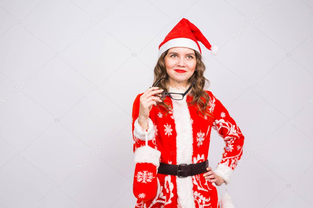 Christmas, holidays and people concept - young woman in santa suit took off glasses on white background with copy space
