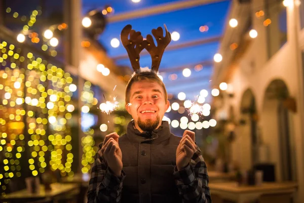 Concepto de Navidad y vacaciones - Hombre feliz en traje de ciervo de Navidad con bengala — Foto de Stock