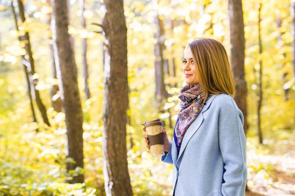 Herfst, de natuur en de mensen concept - mooie jongedame in blauwe vacht die houden van een kopje koffie — Stockfoto