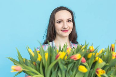 Büyük bir demet lale mavi zemin üzerine beyaz genç kadın