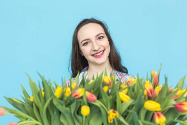 Büyük bir demet lale mavi zemin üzerine beyaz genç kadın