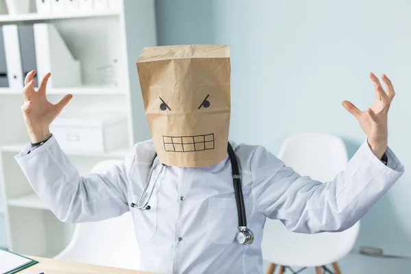 Здравоохранение, медицина и люди концепция - онлайн врач в бумажной маске с грустным лицом сидит за столом с ноутбуком — стоковое фото