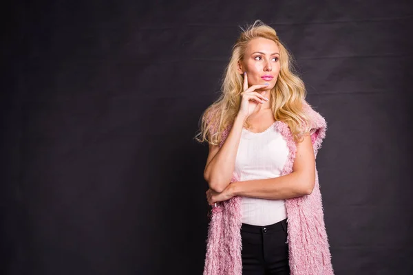 美容, 时尚和人的概念-年轻的金发女子思考的东西在粉红色大衣黑色背景与复制空间 — 图库照片