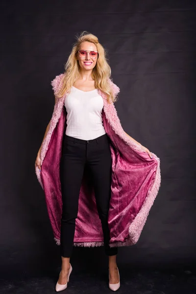뷰티, 패션, 사람들 개념-안경 분홍색 모피 코트에 서 서 검은색에 웃 고 있는 젊은 금발 여자 — 스톡 사진