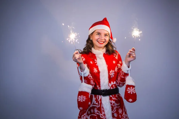 Les gens, Noël et vacances concept - jeune femme en costume de Père Noël avec des bengals sur fond gris — Photo