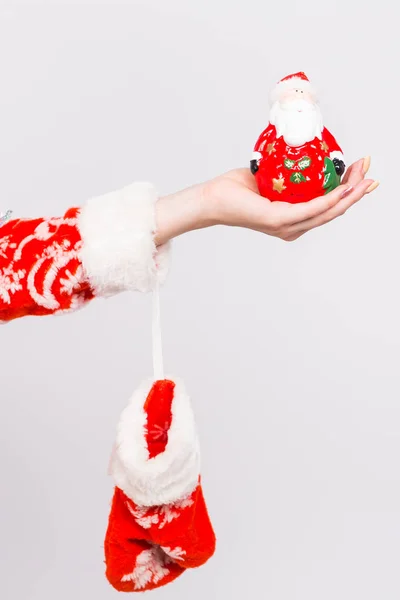 Navidad, celebración, concepto de la gente - Primer plano de la mano de las mujeres sosteniendo una figura de Santa sobre fondo blanco — Foto de Stock