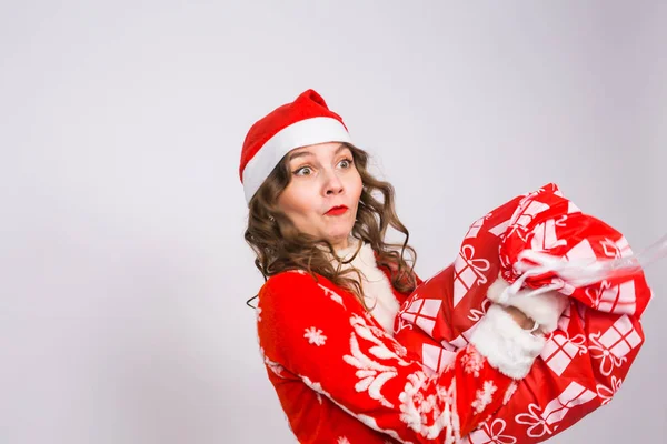 Διακοπές, Χριστούγεννα και άνθρωποι έννοια - γυναίκα με επιφώνημα έκπληξης του γελαστούλη στο santa κοστούμι με τσάντα παρουσιάζει — Φωτογραφία Αρχείου