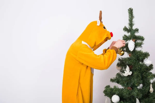 Piada, Natal, conceito de pessoas - homem de traje de veado decorando árvore de xmas no fundo branco — Fotografia de Stock