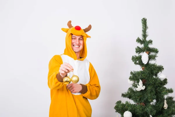 Жарти, різдво, концепція людей - людина в костюмі оленя, що прикрашає ялинку на білому тлі — стокове фото