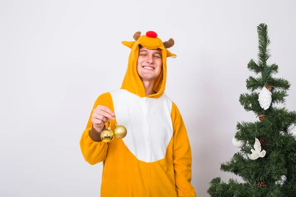 Жарти, різдво, концепція людей - людина в костюмі оленя, що прикрашає ялинку на білому тлі — стокове фото