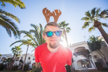 Tatil ve insanlar kavramı - Noel geyik boynuzları açık havada gülümseyen genç çekici adam