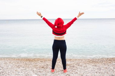 Noel ve tatil kavramı - Noel Baba kostüm fan deniz arka plan arkadan görünüm üzerinde sahip mutlu kadın
