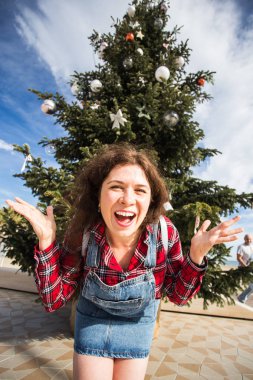 İnsanlar, tatil ve eğlence kavramı - genç kadın Noel ağacı yakınındaki eğlenceli olduğu için mutlu
