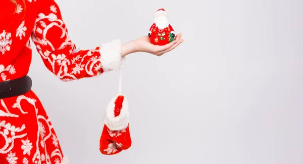 Navidad, celebración, concepto de la gente - Primer plano de la mano de las mujeres sosteniendo una figura de Santa sobre fondo blanco — Foto de Stock