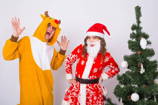 Concept amusant, Noël et vacances - femme heureuse en costume de Père Noël avec l'homme en costume de cerf va vous féliciter avec joyeux Noël — Photo