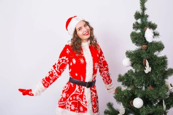 Eğlenceli, Noel ve tatil kavramı - beyaz arka plan ve Noel ağacı karşı Noel Baba olarak giymiş mutlu gülen kadın — Stok fotoğraf
