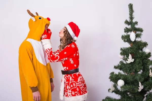 Vacances, Noël et concept de blague - Homme drôle en costume de cerf et femme en costume de Père Noël sont fous autour près de l'arbre de Noël — Photo