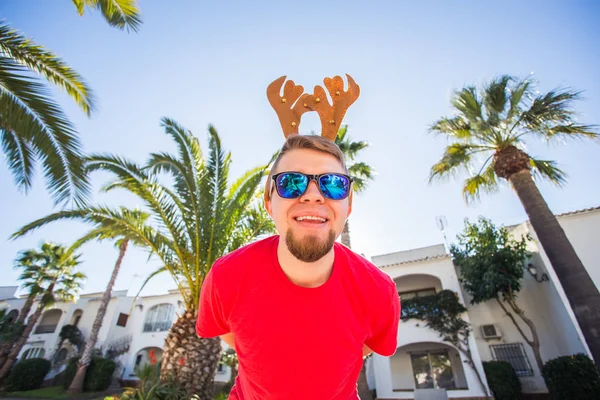 Bayram, yılbaşı ve insanlar kavramı - erkek geyik boynuzları ve dans gözlük ve smilng.