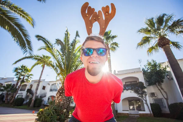 Tatil ve insanlar kavramı - Noel geyik boynuzları açık havada gülümseyen komik adam