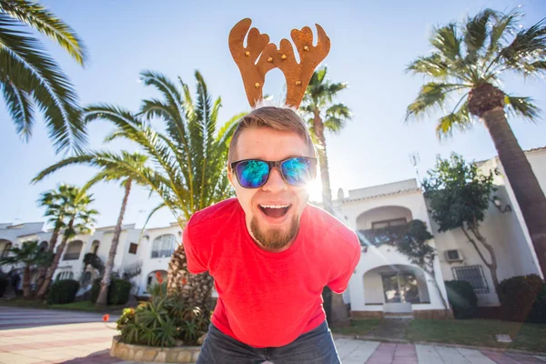 Noel, eğlence ve tatil kavramı - gülümseyen Noel geyik boynuzları açık havada giyen adam