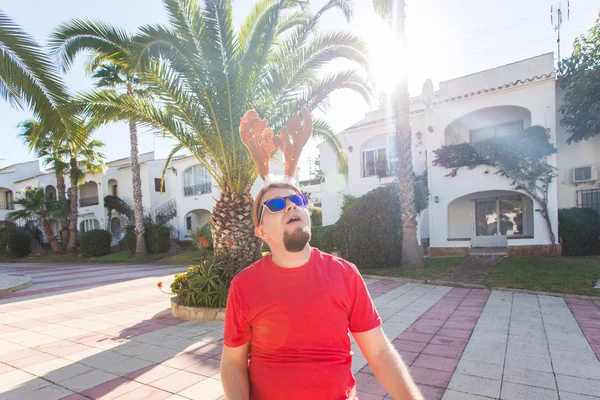 Tatil ve insanlar kavramı - Noel geyik boynuzları açık havada gülümseyen genç çekici adam