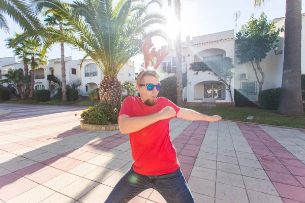 Bayram, yılbaşı ve insanlar kavramı - erkek geyik boynuzları ve dans gözlük ve smilng.