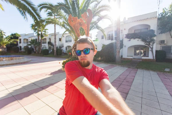 Bayram, yılbaşı ve insanlar kavramı - erkek geyik boynuzları ve dans gözlük ve smilng.