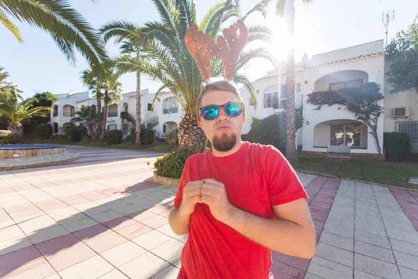 Vacaciones, Navidad y concepto de personas - hombre en cuernos de ciervo y gafas bailando y smilng . — Foto de Stock