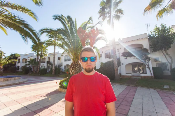 Tatil ve insanlar kavramı - Noel geyik boynuzları açık havada gülümseyen genç çekici adam