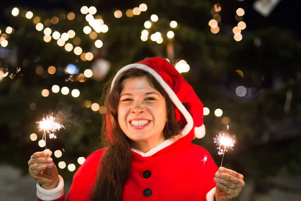 Concept vacances - Femme souriante en costume de Noël avec des lumières ou des étincelles dans ses mains — Photo