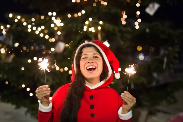 İnsanlar, tatil ve Noel kavramı - Noel Baba kostüm maytap veya Bengal ışık ile genç kadın — Stok fotoğraf