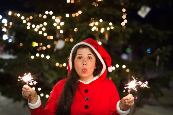 Urlaubskonzept - lächelnde Frau im Weihnachtskostüm mit Lichtern oder Funkeln in den Händen — Stockfoto