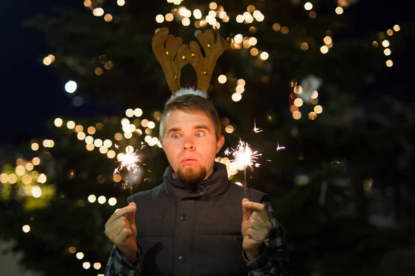 Concepto de Navidad y vacaciones - Hombre feliz en traje de ciervo de Navidad con bengala — Foto de Stock