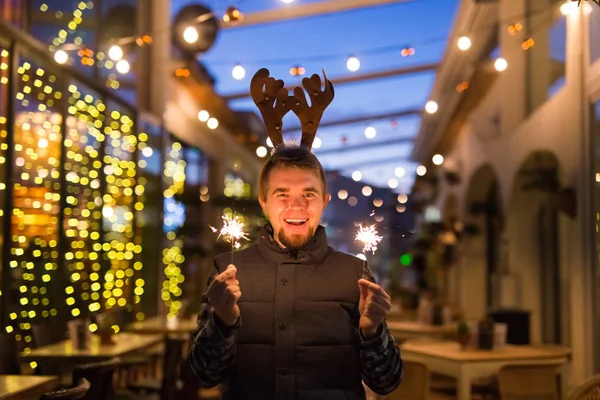 Christmas and holiday concept - Happy man in Christmas deer costume with sparkler