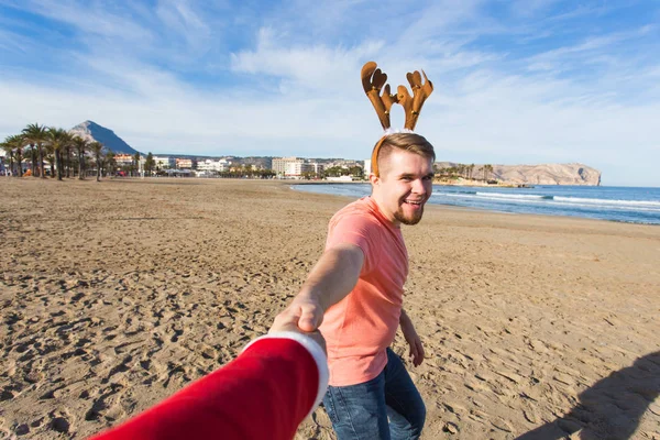 Eğlenceli, tatil ve kavram - Noel geyik boynuzları sahilde mutlu adam peşimden