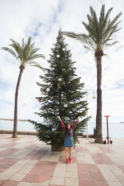 Natal, feriados, humor e conceito de pessoas - jovem mulher feliz se divertir sob a árvore de Natal — Fotografia de Stock