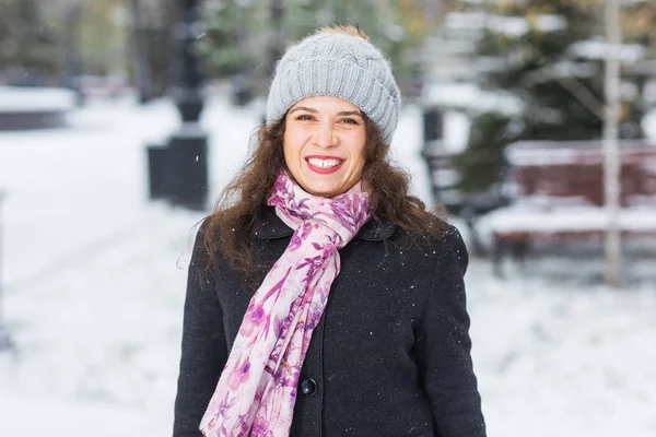 Kış ve insanlar kavramı - şapka ve atkı açık havada gülümseyen genç kadın portresi