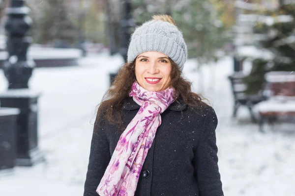 Winter en mensen concept - portret van een jonge vrouw in de muts en sjaal glimlachend buitenshuis — Stockfoto