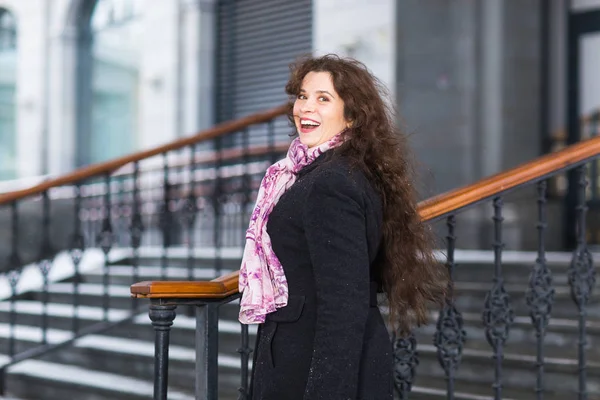 Mensen, mode en winter concept - jonge vrouw poseren in jas met op de achtergrond van de trap — Stockfoto