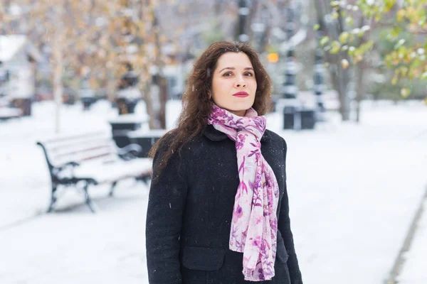 Stad, winter en mensen concept - mooie gelukkig jonge vrouw in zwarte jas en roze sjaal in besneeuwde park — Stockfoto