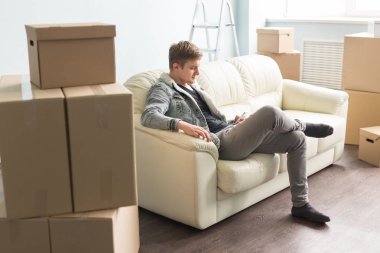 Yer değiştirme, yeni ev ve gayrimenkul konsept - yakışıklı delikanlı taşıdıktan sonra smartphone kullanarak yeni ev