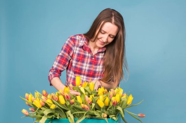 Lale mavi arka plan üzerinde kutu ile neşeli genç kadın çiçekçi
