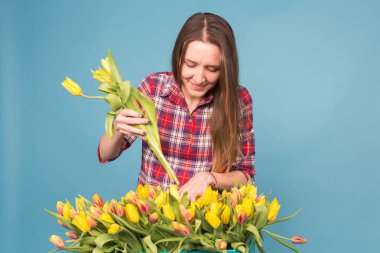 Büyük kutu mavi zemin üzerine sarı laleler ile genç kadın çiçekçi