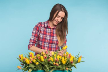 Büyük kutu mavi zemin üzerine sarı laleler ile genç kadın çiçekçi