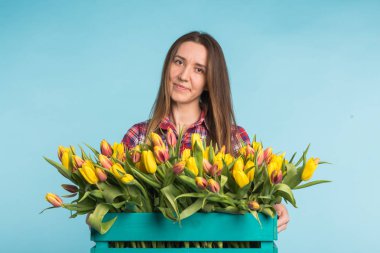 Lale mavi zemin üzerine kutusuyla tutan mutlu beyaz genç kadın